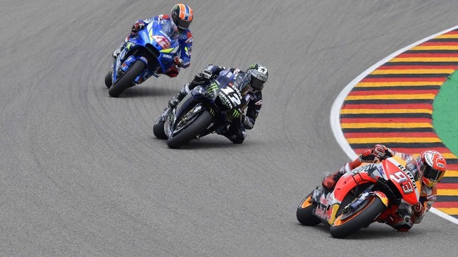 Repsol Honda Team's Spanish rider Marc Marquez (R) steers his bike in front of Monster Energy Yamaha' Spanish rider Maverick Vinales (C) and Suzuki Ecstar's Spanish rider Alex Rins during the Moto GP Grand Prix Germany at the Sachsenring Circuit on July 7, 2019 in Hohenstein-Ernstthal, eastern Germany. (Photo by Tobias SCHWARZ / AFP)
