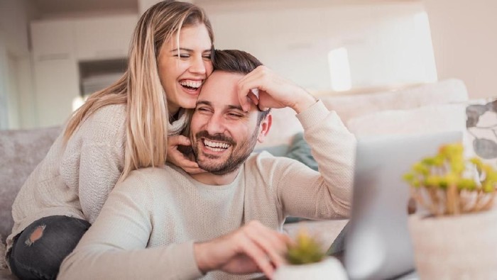 Close up of young couple working on laptop at home.