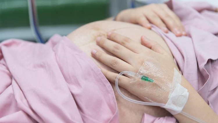 Asian Pregnant Woman patient is on drip receiving a saline solution on bed VIP room at hospital, selective focus.
