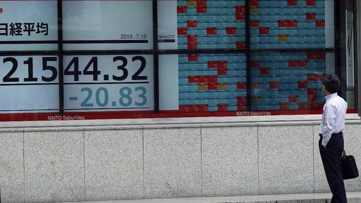 People walk past an electronic stock board showing Japan's Nikkei 225 index at a securities firm in Tokyo Wednesday, July 10, 2019. Asian shares were mostly higher Wednesday in cautious trading ahead of closely watched congressional testimony by the U.S. Federal Reserve chairman. (AP Photo/Eugene Hoshiko)