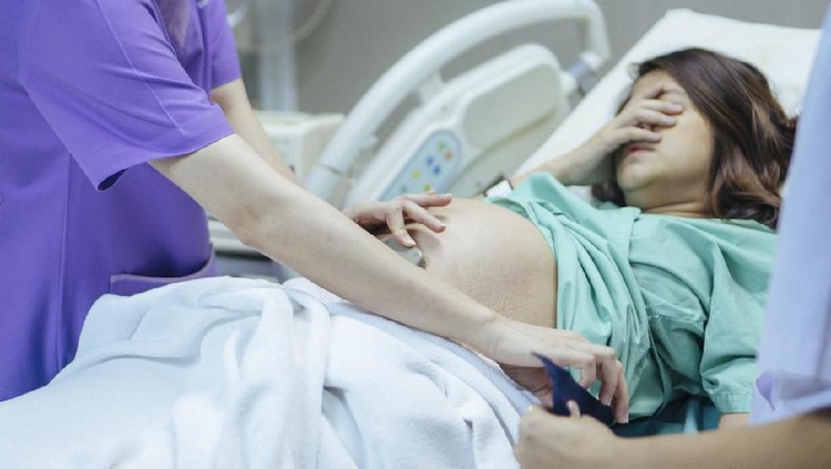ibu hamil Doctor examining belly of expectant mother in hospital room. Thailand.