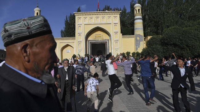 This photo taken on June 5, 2019 shows Uighur men dancing after Eid al-Fitr prayers, marking the end of Ramadan, outside the Id Kah mosque in Kashgar, in China's western Xinjiang region. - In China's Xinjiang, a northwest region tightly controlled by police, authorities have created a parallel universe for tourists and locals -- a place where travellers sightsee just a stone's throw from internment camps. (Photo by GREG BAKER / AFP) / TO GO WITH: China-rights-tourism-Xinjiang, FEATURE by Eva XIAO