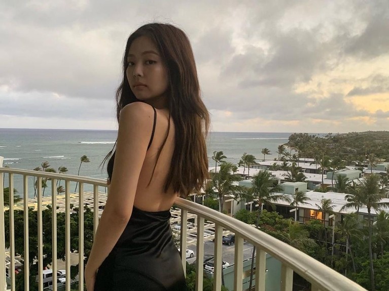 Jennie berpose dengan gaun punggung terbuka dengan latar pemandangan pantai.