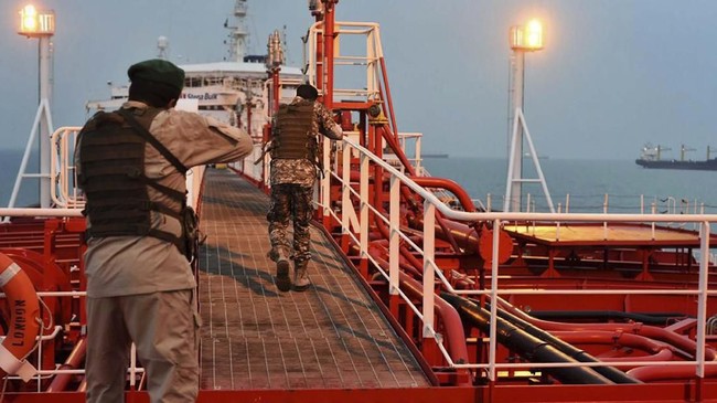 In this Sunday, July 21, 2019 photo, two armed members of Iran's Revolutionary Guard inspect the British-flagged oil tanker Stena Impero, which was seized in the Strait of Hormuz on Friday by the Guard, in the Iranian port of Bandar Abbas. Global stock markets were subdued Monday while the price of oil climbed as tensions in the Persian Gulf escalated after Iran's seizure of a British oil tanker on Friday. (Morteza Akhoondi/Mehr News Agency via AP)
