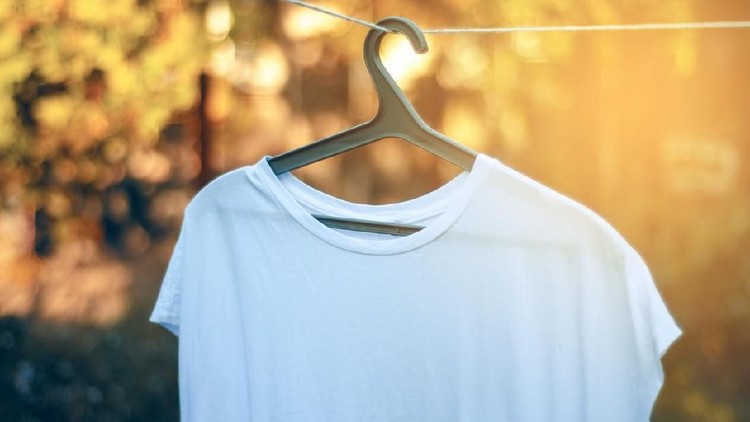 Senior washwoman hanging a shirt on the hanger standing in the professional laundry