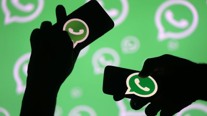 Men pose with smartphones in front of displayed Whatsapp logo in this illustration September 14, 2017. REUTERS/Dado Ruvic