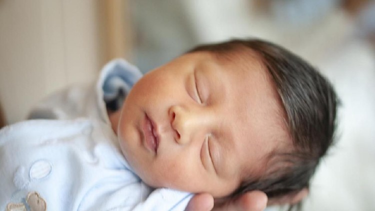 bayi laki-laki Turkish newborn sleeping in his mother's arm