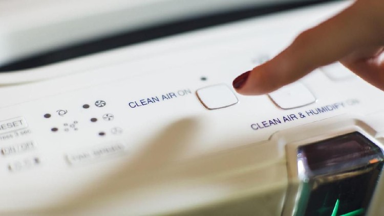 Close-up of female hand turning on an air purifier and ionizer