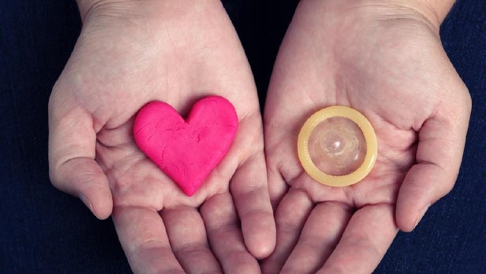 young woman pierces a condom