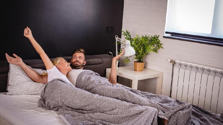 A young couple wakes with a smile in bed in the morning