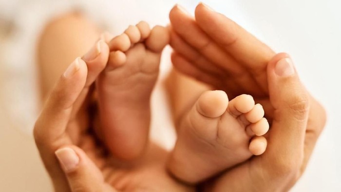 Photo of newborn baby feet. Baby feet covered in blue cotton isolated background. Tiny foot of newborn baby in soft selective focus.