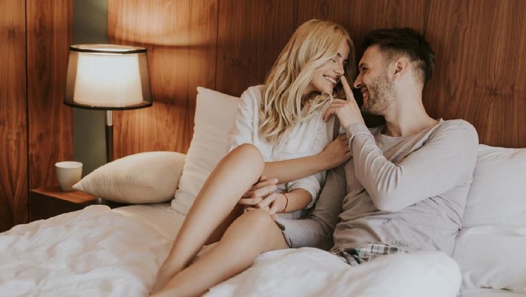 Attractive young asian couple woman and man smiling and lying on bed together with bonding love and passion feeling happy and satisfied. Young flirting married asian romance lifestyle at home concept.