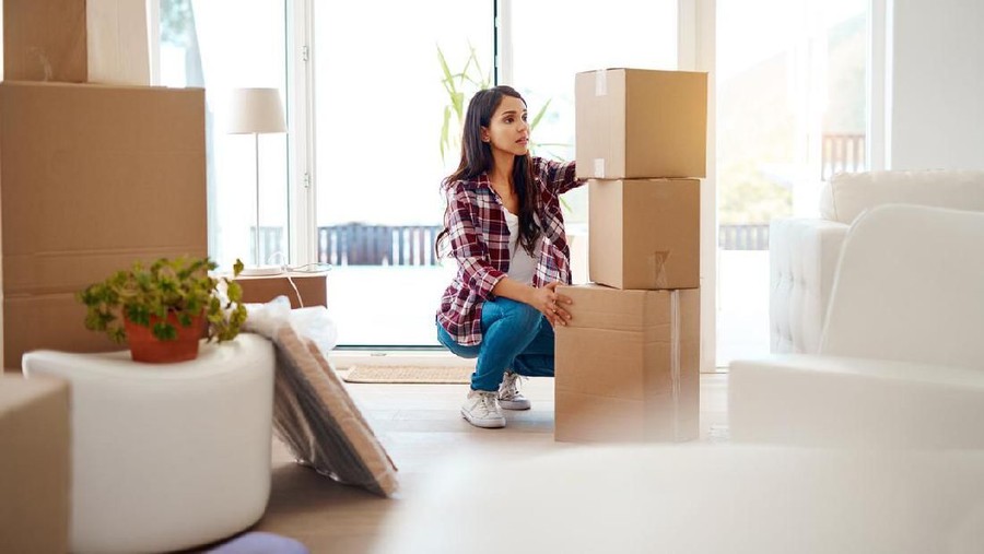 Full length shot of an attractive young woman stacking boxes while moving house