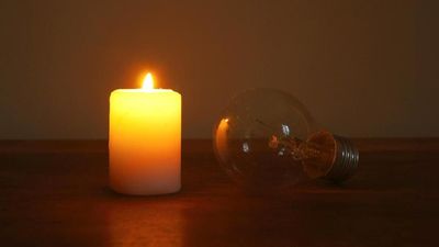Burning candle and lamp on desktop in darkness (no electricity). Troubles with electricity after storm.