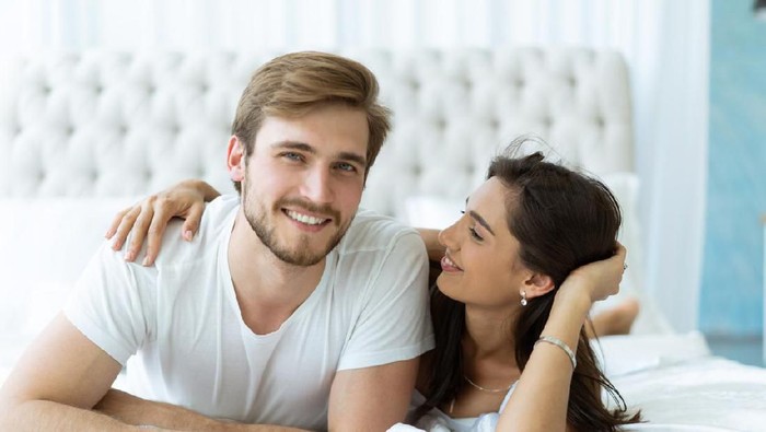 Young happy couple lying together in bed