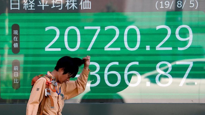 Passersby are reflected on an electronic board showing the exchange rates between the Japanese yen and the U.S. dollar, the yen against the euro, the yen against the Australian dollar, Dow Jones Industrial Average and other market indices outside a brokerage in Tokyo, Japan, August 6, 2019.   REUTERS/Issei Kato