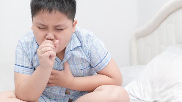 Cute little blond girl coughing in her elbow isolated on white- the technique  recommended by the U.S. Centers for Disease Control and Prevention and the American Academy of Pediatrics.