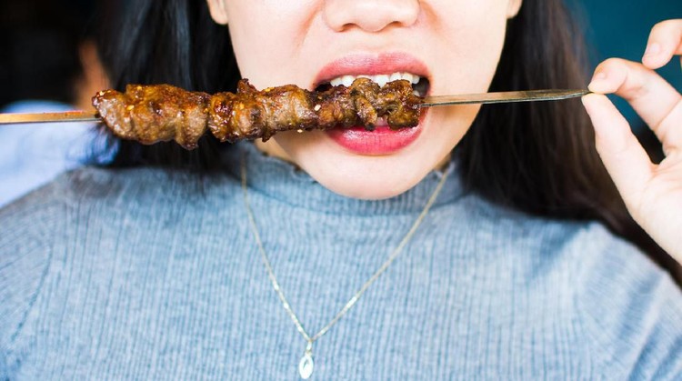 Woman eating Chinese barbeque close up