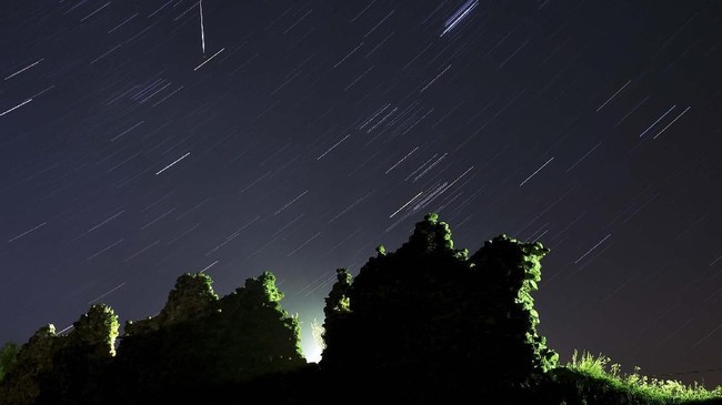 A long exposure picture shows a Perseid meteor crossing the night sky and stars trails above the ruins of a medieval castle in the village of Kreva, some 100 km northwest of Minsk, on August 12, 2019. (Photo by Sergei GAPON / AFP)