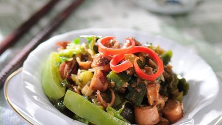 Cumi Kawanua, the traditional Minahasan dish of squid and tomato stew. Whole squids stewed in its own juice with tomatoes, chili peppers, and green onion. The stew is served on a ceramic bowl and garnished with basil leaves. A plate of darker monotone color underlines the bowl. Some kaffir lime leaves are left on the plate.