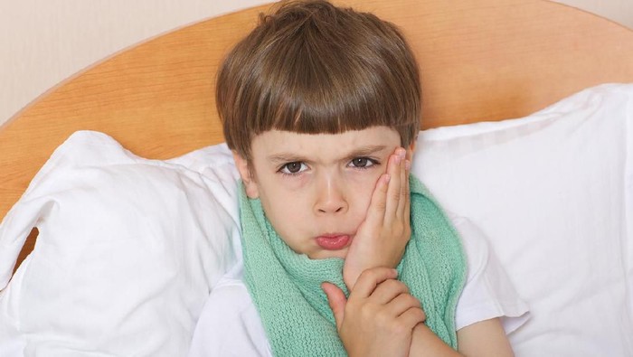 One year old baby crying in bed with a teddy bear