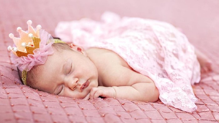 Little baby girl lies on a pink background. Photo session of a newborn baby. Professional newborn photography.