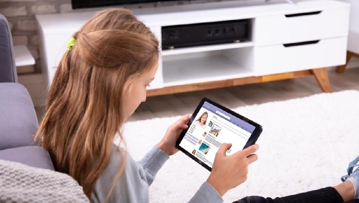 Close-up Of A Girl Using Social Networking Site On Digital Table At Home