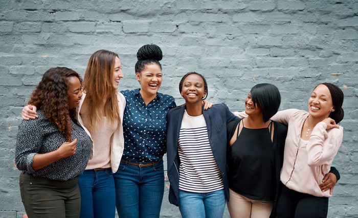 Portrait of a diverse group of young women standing together against a gray wall outside