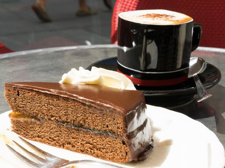 Slice of Sachertorte or Chocolate cake served with fresh cream and coffee
