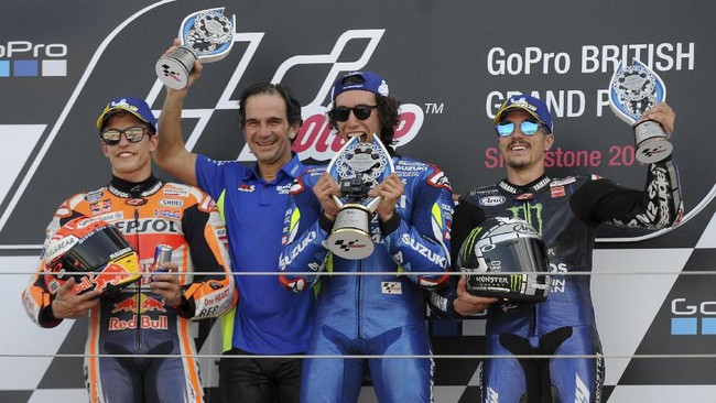 Race winner Spain's rider Alex Rins of the Team SUZUKI ECSTAR, second right, celebrates on a podium with the team principal Davide Brivio, second left, second placed Spain's rider Marc Marquez of the Repsol Honda Team, left, and third placed Spain's rider Maverick Vinales of the Monster Energy Yamaha MotoGP after the MotoGP race at the British Motorcycle Grand Prix at the Silverstone racetrack, in Silverstone, England, Sunday, Aug. 25, 2019. (AP Photo/Rui Vieira)
