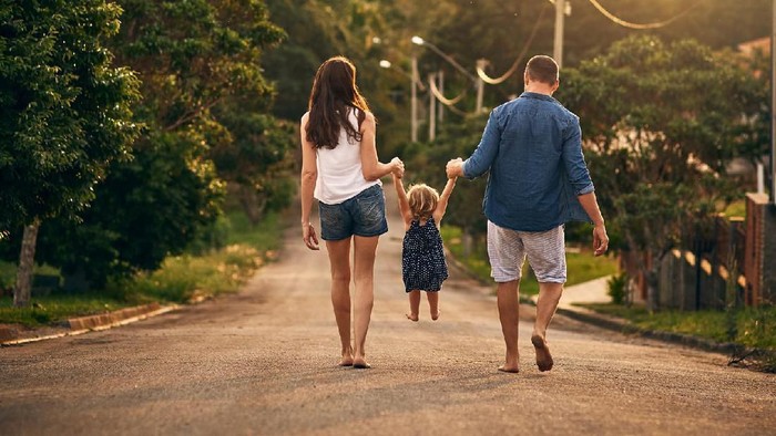 Rearview shot of an unrecognizable family taking a walk down the road outside