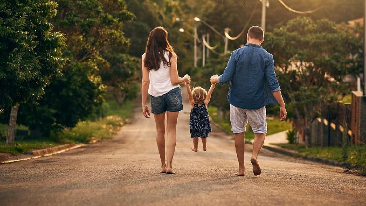 Rearview shot of an unrecognizable family taking a walk down the road outside