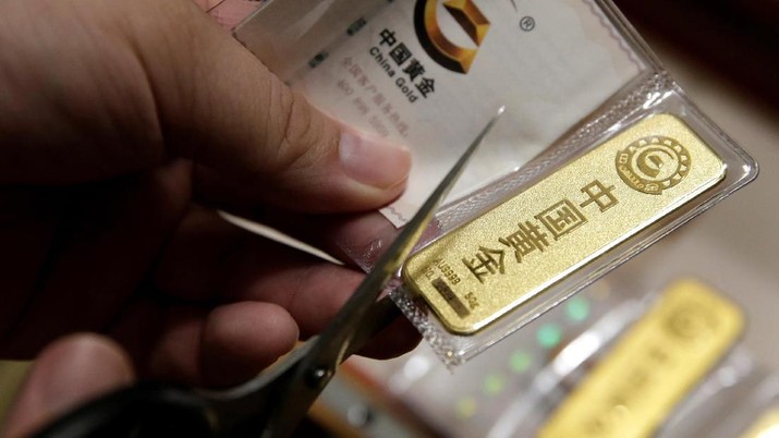 A man cuts open the bag after he bought 50 gram gold bars as an investment in Beijing, China, August 5, 2019. Picture taken August 5, 2019.REUTERS/Jason Lee