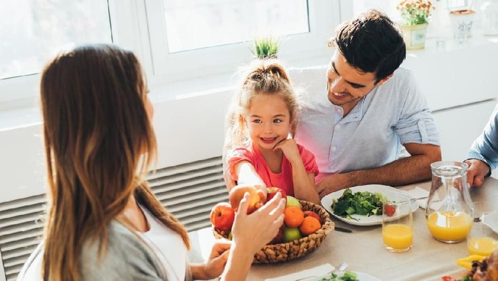 Smiling child girl happy  face sitting indoors at table eating vegetable fruit salad.Healthy kid's nutrition background empty copy space.