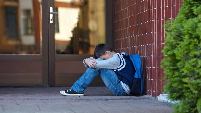 Schoolboy crying in the yard of the school. Negative emotion.