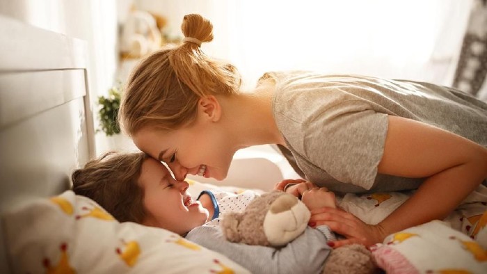 morning awakening. mother wakes her daughter in bed in morning