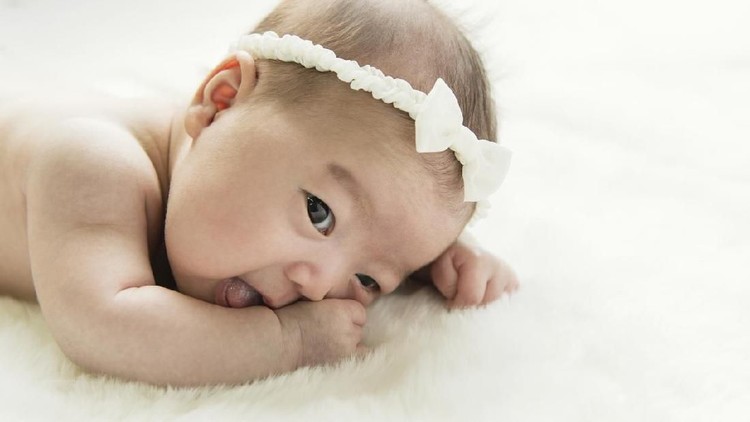 Cute newborn baby girl lying in the bed. 2 month old child in owl hat sleeping on blue blanket with stars