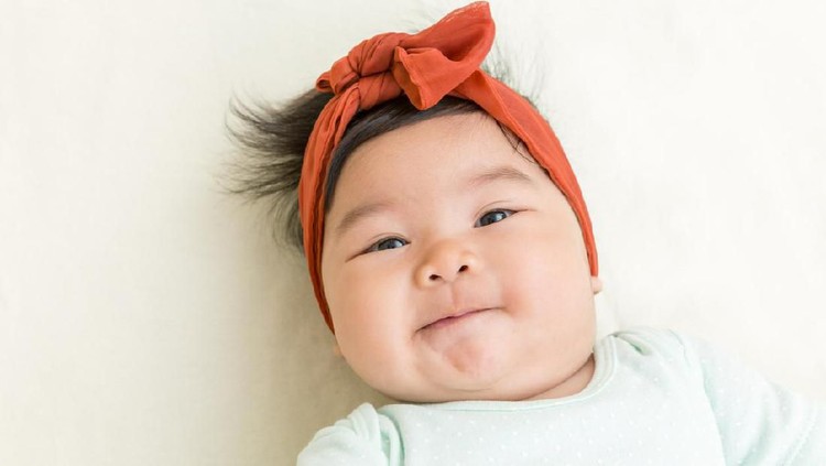 Adorable asian baby smiling on the bed.