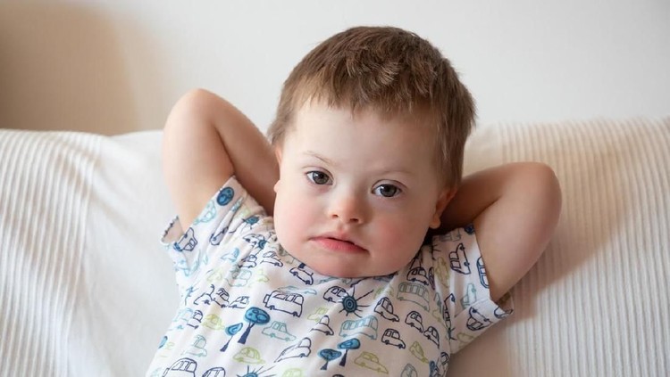 Portrait of cute small boy with Down syndrome at home