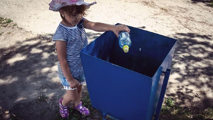 Cute little Asian 18 months / 1 year old toddler baby boy child throwing plastic bottle in recycling trash bin at public park, Eco friendly kid Recycling, Save the world & environment concept