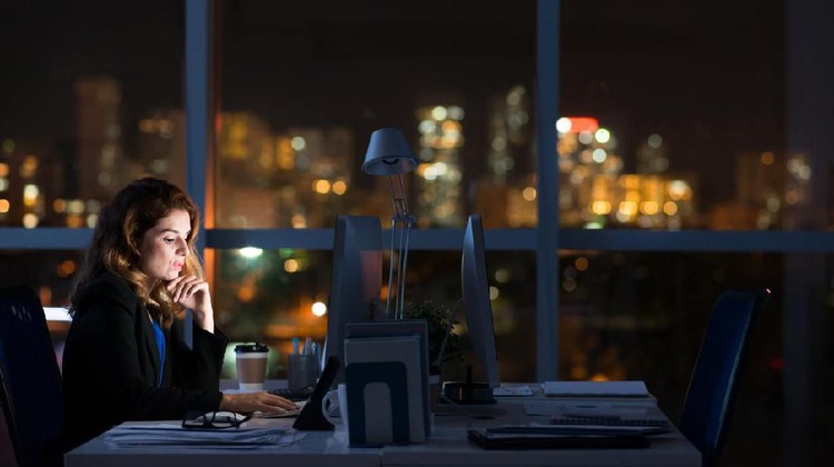 Pretty business woman working alone in dark office