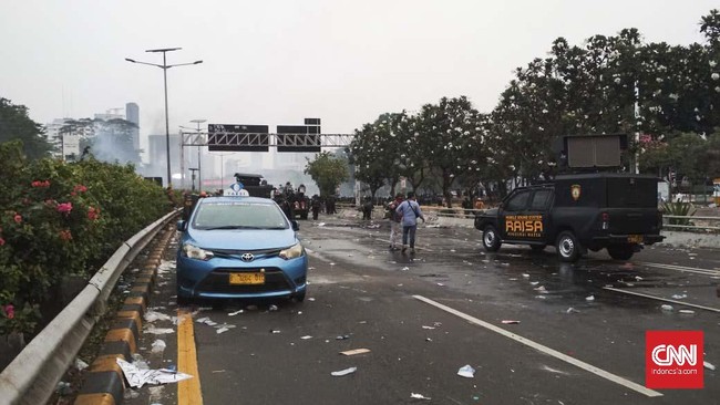Terjebak bentrok mahasiswa dan polisi, seorang sopir taksi meninggalkan mobilnya begitu saja di bahu jalan Tol Dalam Kota seberang DPR.