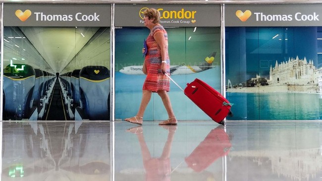 A passenger walks past a closed Thomas Cook office at Palma de Mallorca airport on Monday, Sept. 23, 2019. Spain's airport operator AENA says that 46 flights have been affected by the collapse of the British tour company Thomas Cook, mostly in the Spanish Balearic and Canary archipelagos. (AP Photo/Francisco Ubilla)