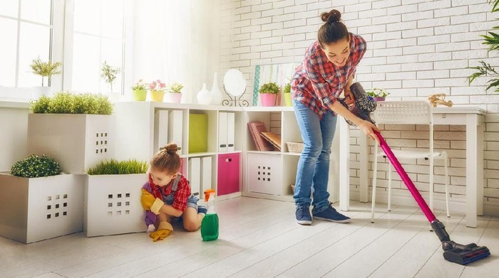 Happy family cleans the room. Mother and daughter do the cleaning in the house. A young woman and a little child girl wiped the dust and vacuumed the floor.