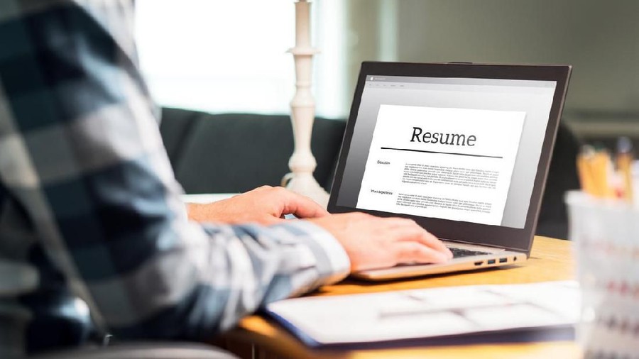 Cari kerja Man writing resume and CV in home office with laptop. Applicant searching for new work and typing curriculum vitae for application. Job seeking, hunt and unemployment. Mock up text in computer screen.