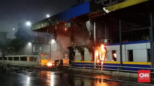 Sejumlah personel kepolisian memadamkan api yang menjalar di sepanjang gerbang tol Pejompongan.