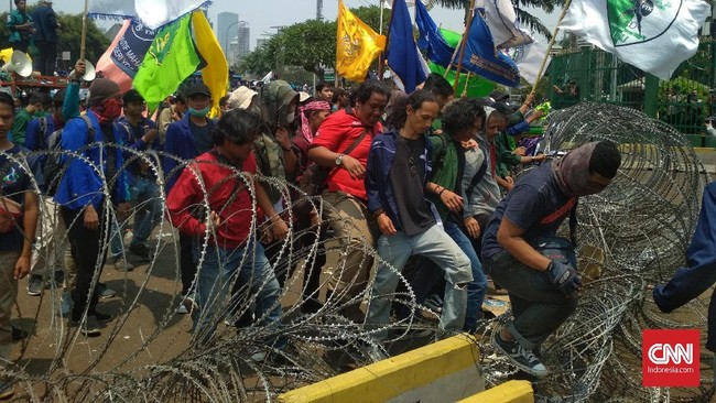 Ribuan mahasiswa mendesak untuk masuk ke gedung dengan cara menggulung kawat berduri yang dibenatngkan oleh polisi agar bisa bertemu dengan pimpinan DPR RI.