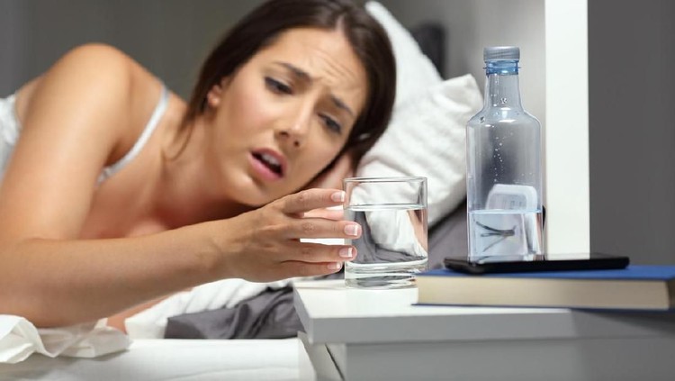 Asian woman in white nightwear drinking water before bedtime for good health at bedroom. Basic concepts in health and health care.