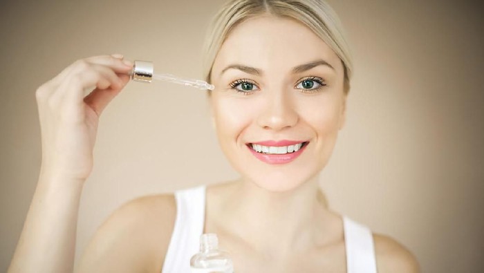 Woman with elegant makeup applying serum treatment. Space for copy.