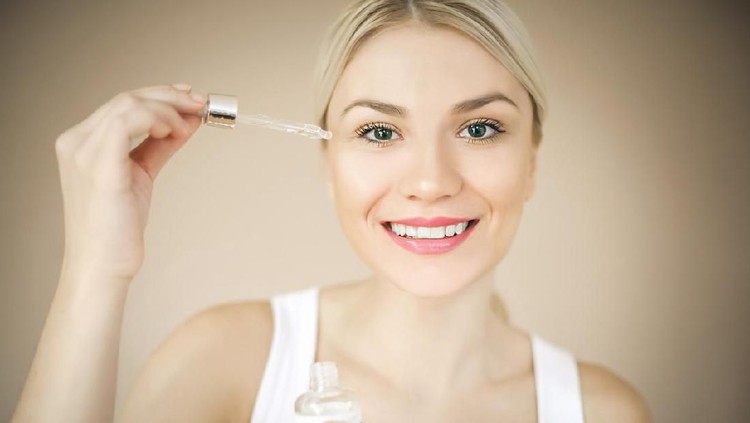 Woman with elegant makeup applying serum treatment. Space for copy.